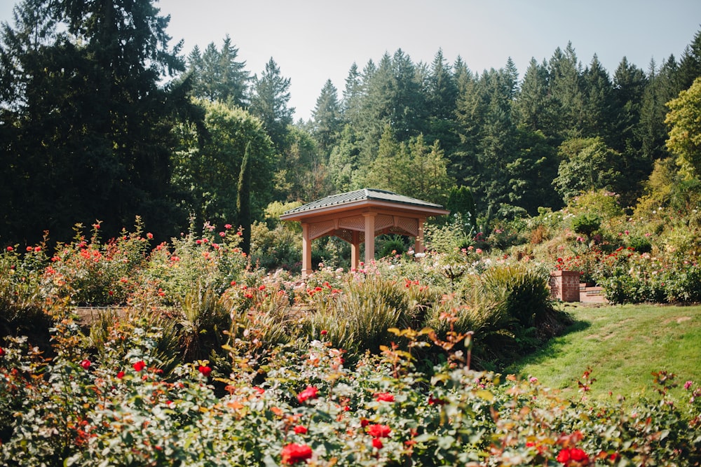 a gazebo surrounded by flowers and trees in a park