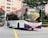A public transit bus in motion on an urban road. The bus has a purple and white color scheme with the SBS Transit logo. It is displaying route number 142 and is surrounded by high-rise residential buildings and greenery.