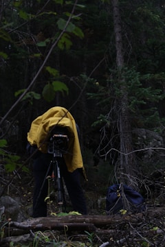 Behind-the-scenes shot of a filmmaker setting up a camera in a forest.