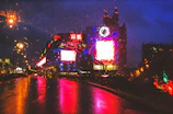 Vibrant city street scene with colorful lights reflecting on wet pavement.