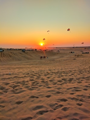 A vibrant desert safari sunset with travelers enjoying the view.