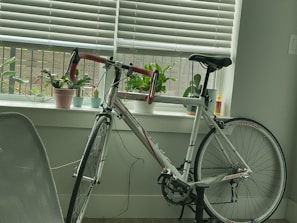 A stationary bike positioned by a sunny window with a water bottle and towel nearby