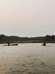 Kayakers paddling gently on a calm lake surrounded by lush greenery.