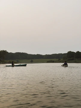 Kayakers paddling gently on a calm lake surrounded by lush greenery.