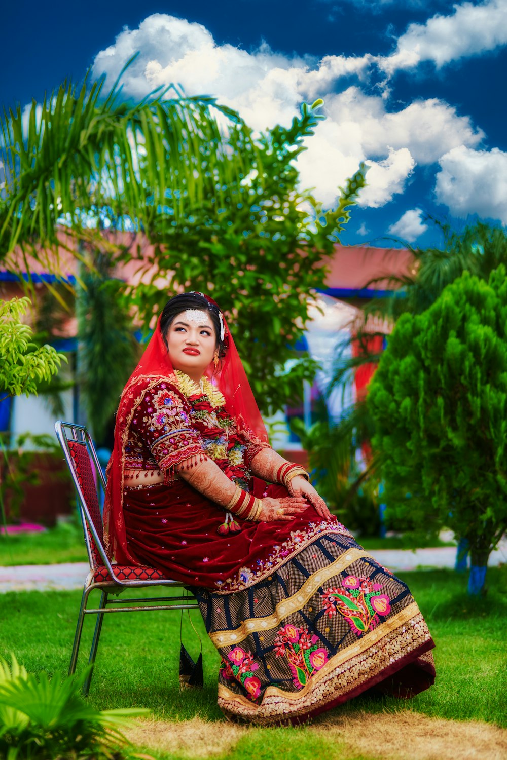 a woman in a red and gold dress sitting on a chair