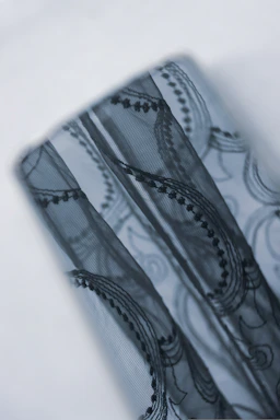 Close-up of luxurious beige and black shapewear fabrics with subtle golden accents on a clean white background