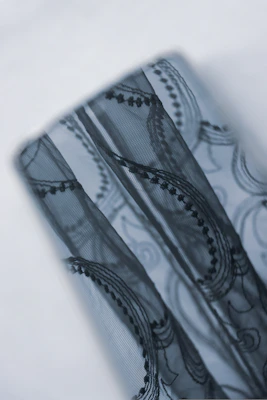 Close-up of a delicate blouse with lace details, styled on a mannequin against a pastel background.