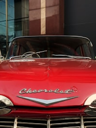 A vibrant display board featuring a shiny red 1957 Chevy Bel Air at a sunny car show.