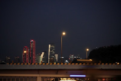 A city skyline at night with red alert lights glowing over government buildings.