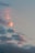 Clouds float across the sky with hues of pink and orange, suggesting a sunset or sunrise. The overall sky is a soft bluish-gray tone.