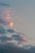 Clouds float across the sky with hues of pink and orange, suggesting a sunset or sunrise. The overall sky is a soft bluish-gray tone.