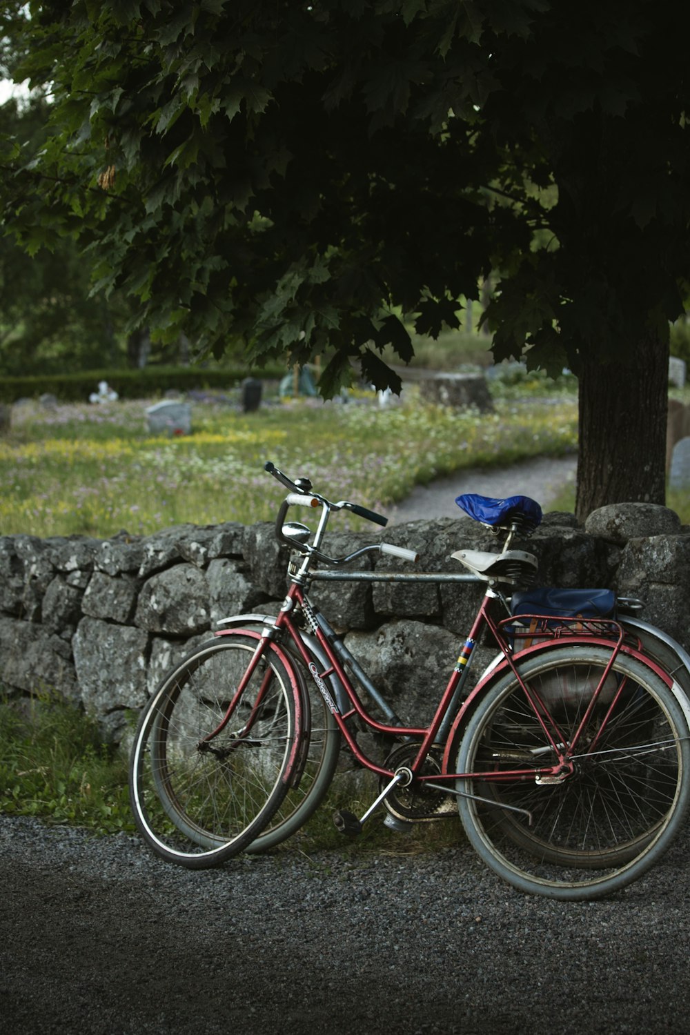 Una bicicleta roja estacionada junto a un muro de piedra