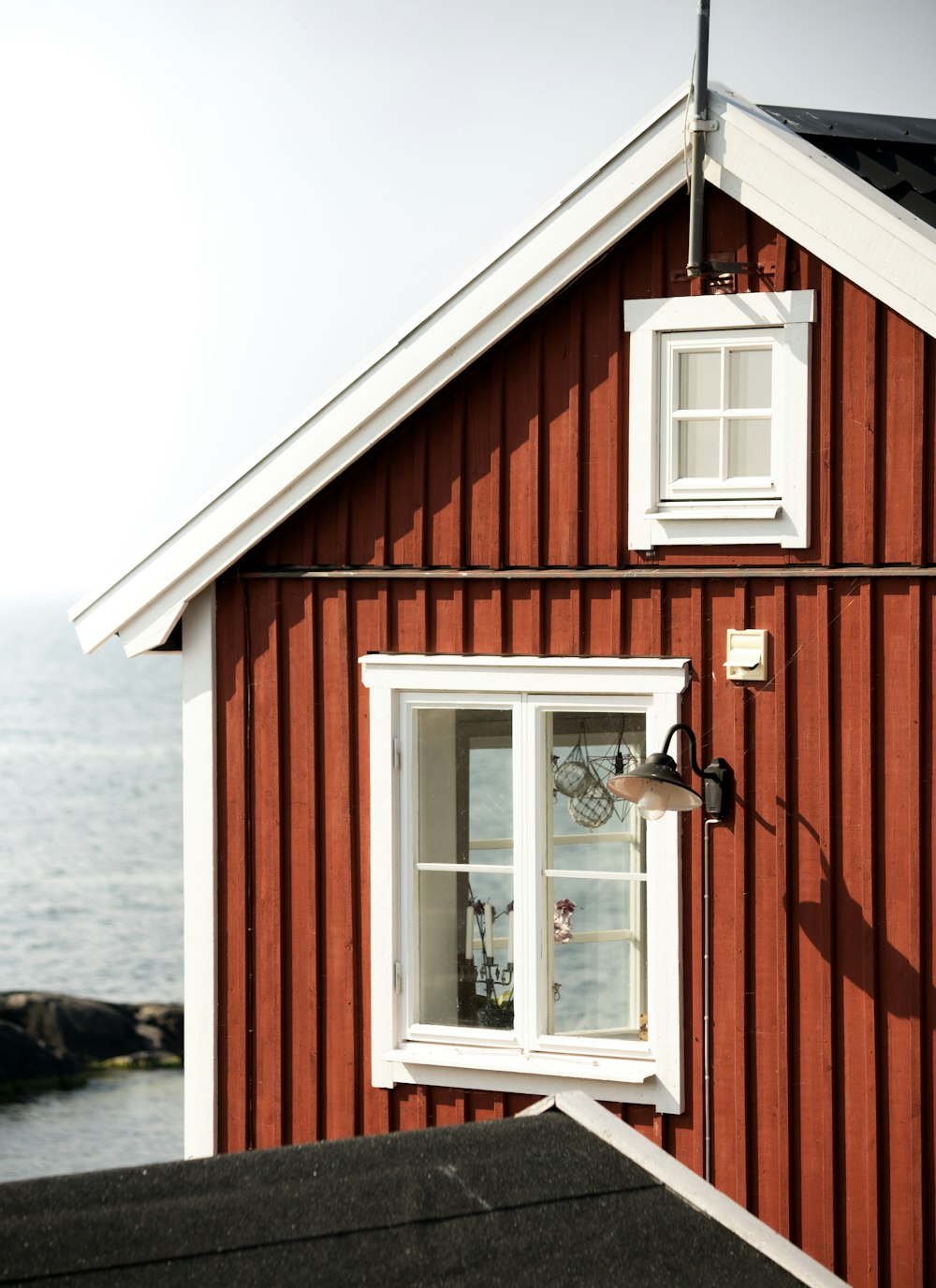 a red house with a white window and a black roof