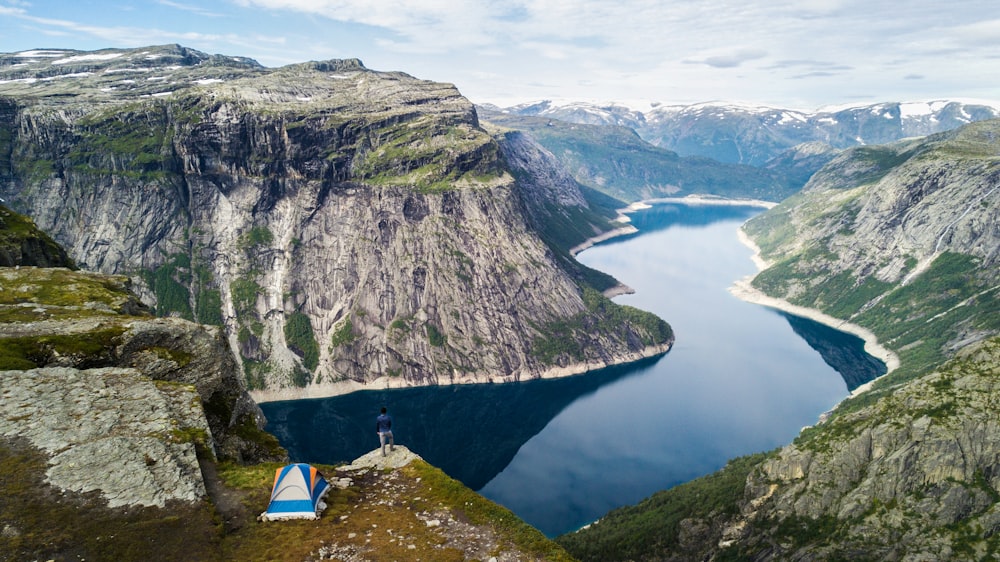 a man standing on top of a mountain next to a body of water