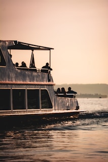 Sunrise view from the deck of a boat with silhouettes of islands in the distance.