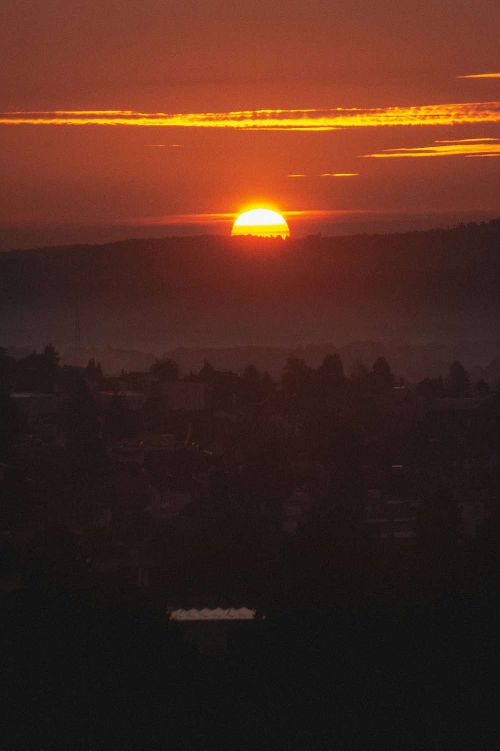 the sun is setting over a city in the distance