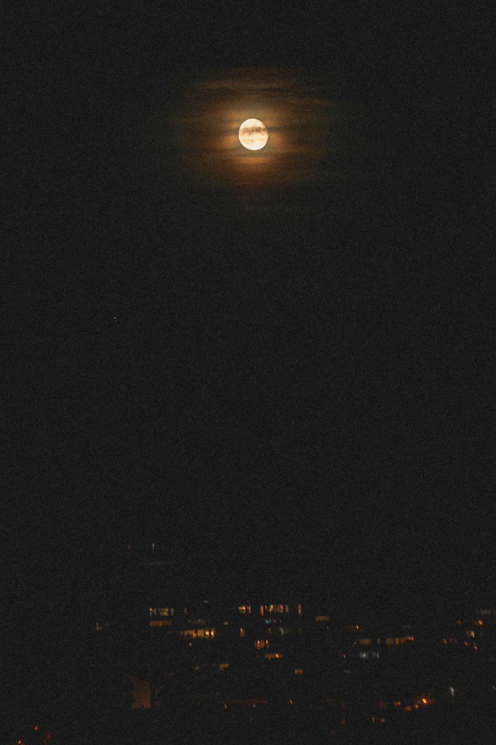 a full moon seen over a city at night