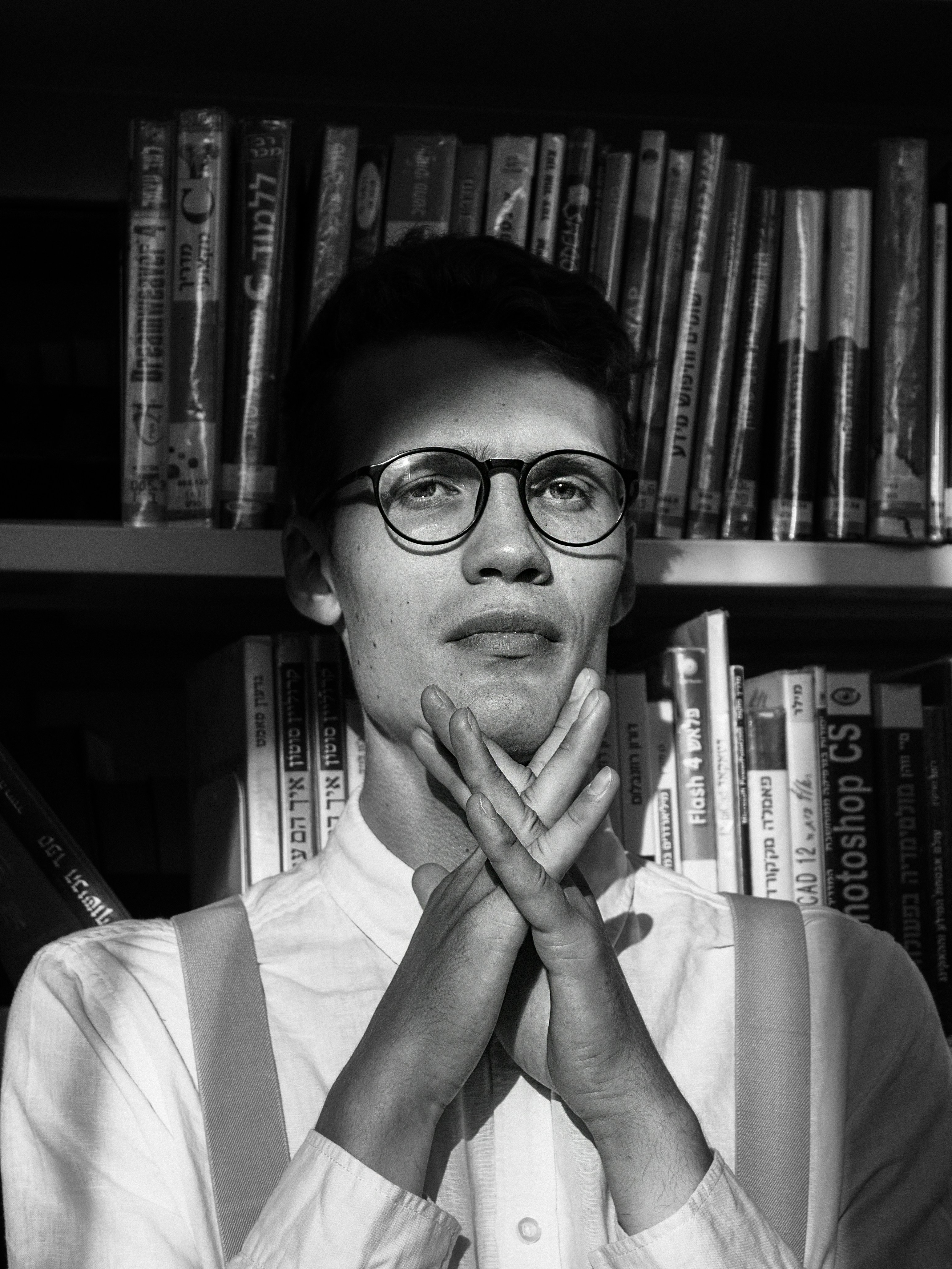 a man wearing glasses standing in front of a bookshelf