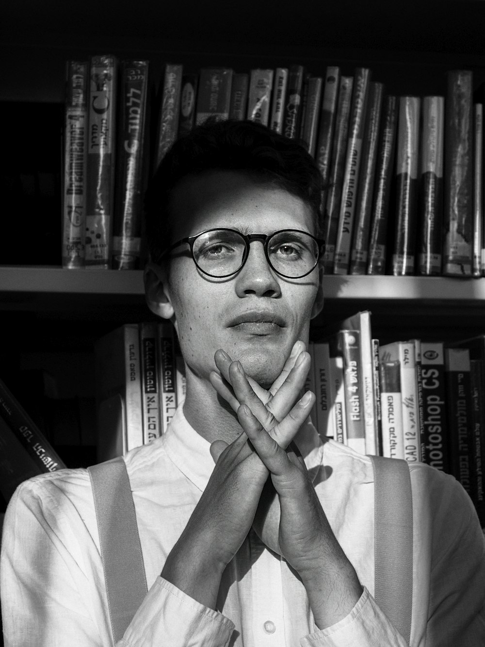 a man wearing glasses standing in front of a bookshelf