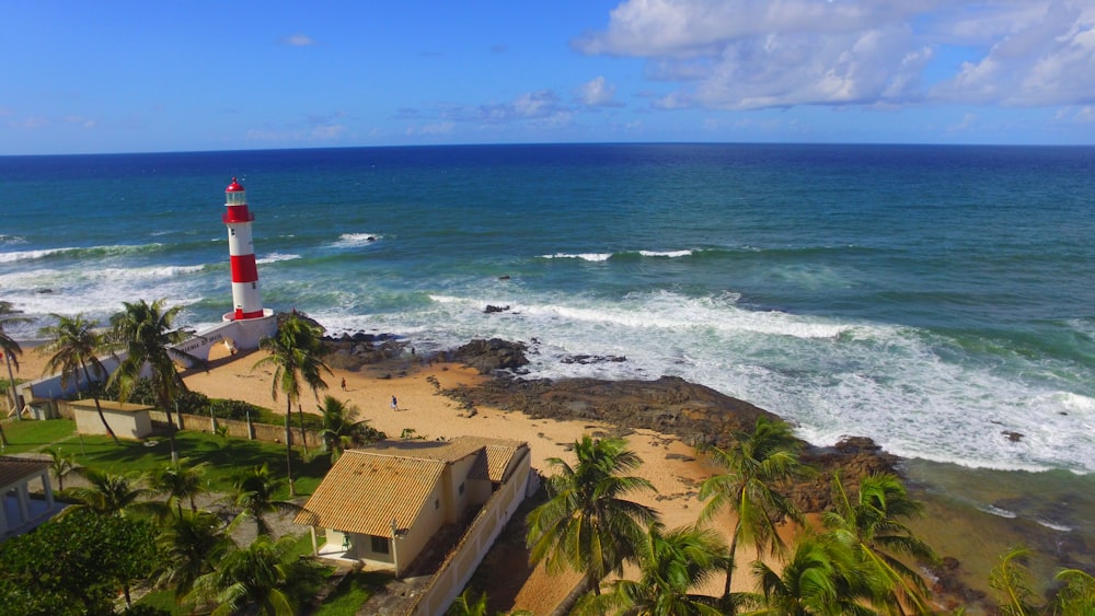 a red and white lighthouse sitting on top of a sandy beach