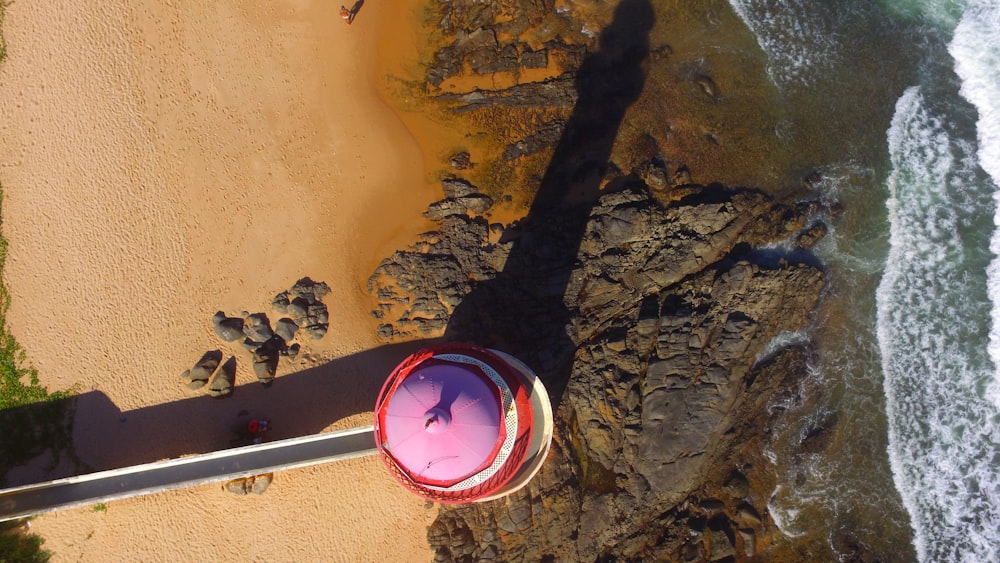 an aerial view of a beach with a pink umbrella