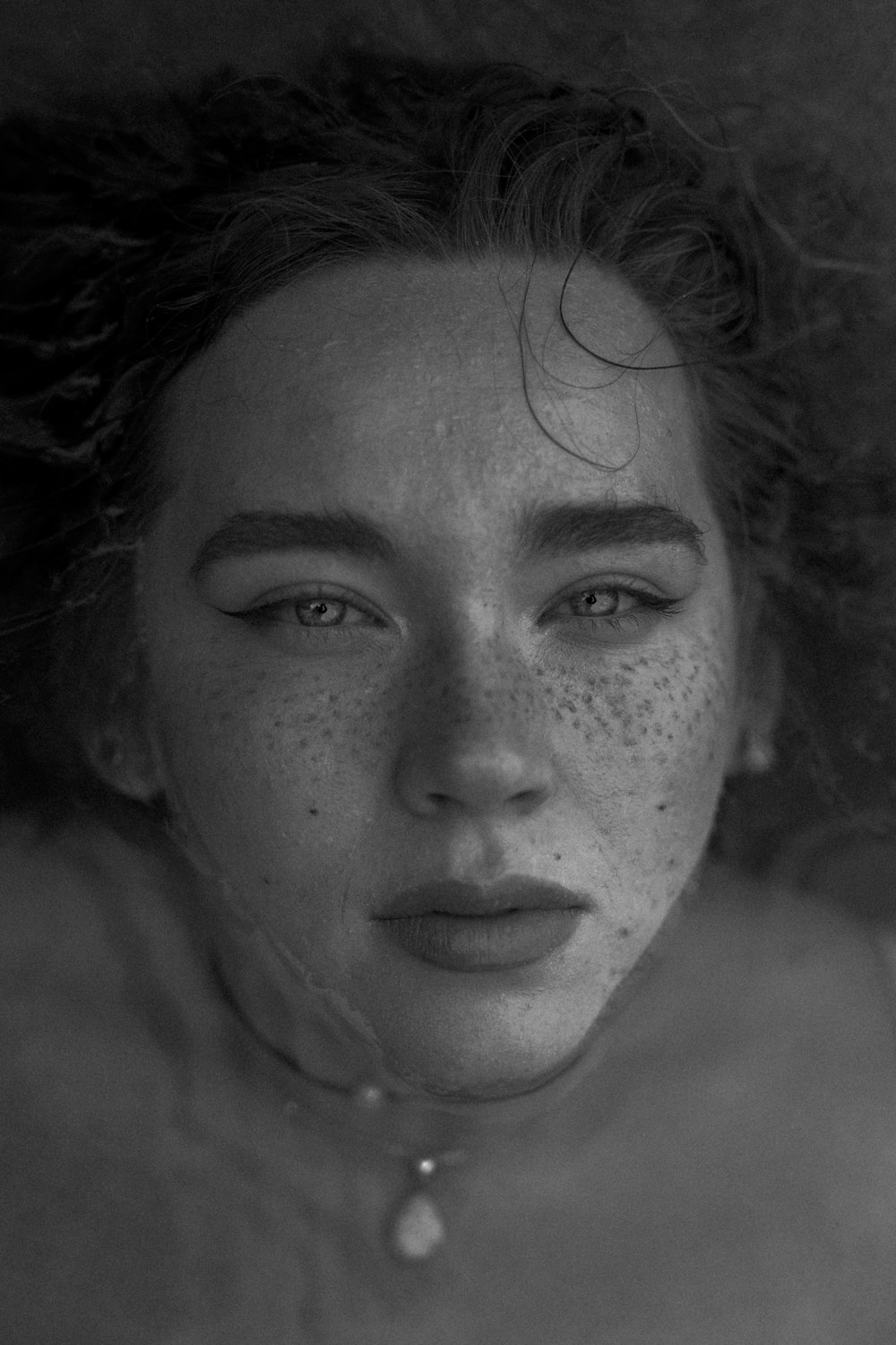 a black and white photo of a woman with freckles on her face