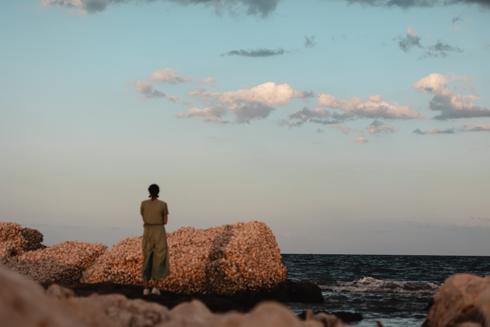 uma pessoa em pé em uma rocha perto do oceano