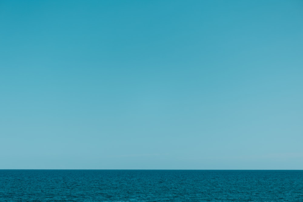 a lone boat floating in the middle of the ocean