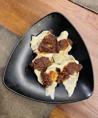 Close-up of steaming mantu dumplings served with a rich tomato sauce and fresh herbs on a rustic plate.