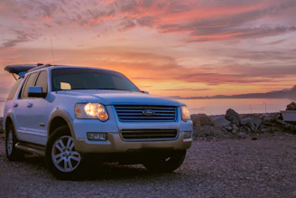 A cozy SUV parked beside a serene mountain lake in Hunza at sunset.