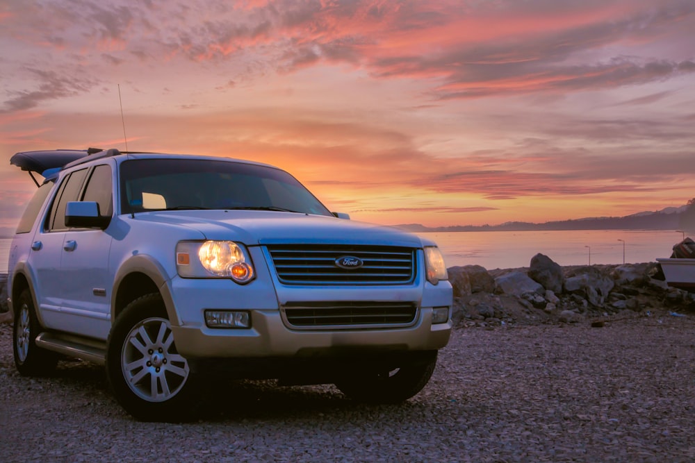 a white suv parked on a rocky beach