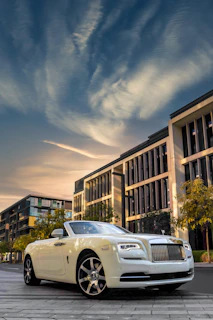 a white rolls royce parked in front of a building