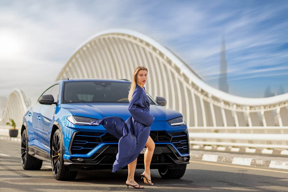 a woman leaning on the hood of a blue sports car