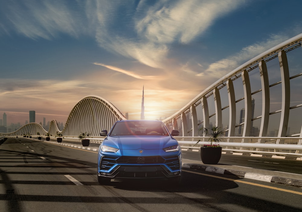 a blue car driving down a highway next to a bridge