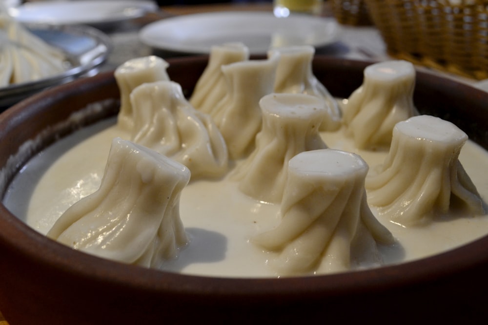 a brown bowl filled with cream covered dessert items