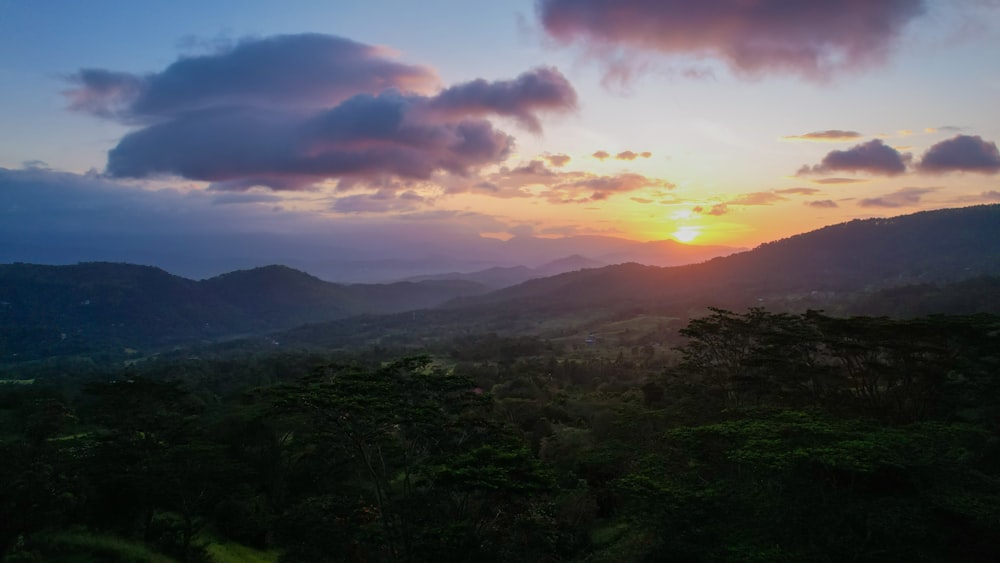 the sun is setting over a mountain range