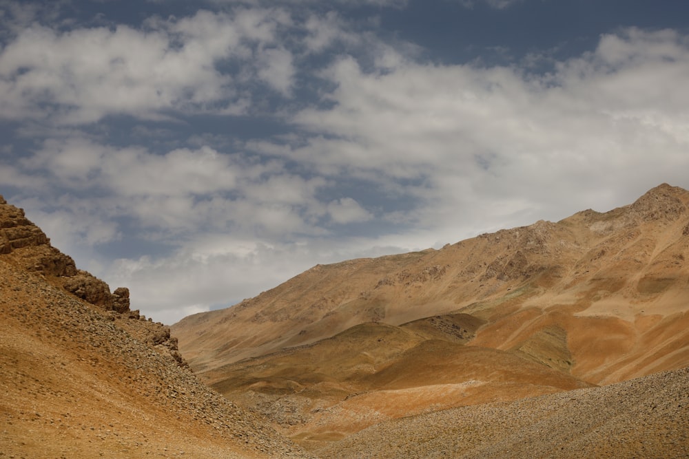 a mountain range in the desert under a cloudy sky