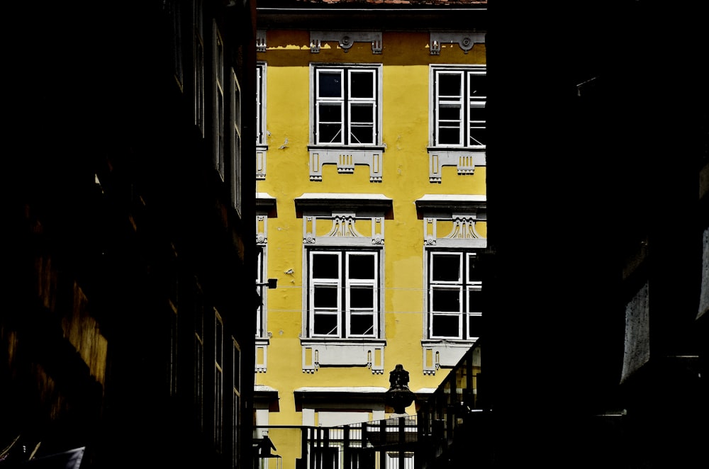 a narrow alley way with a yellow building in the background