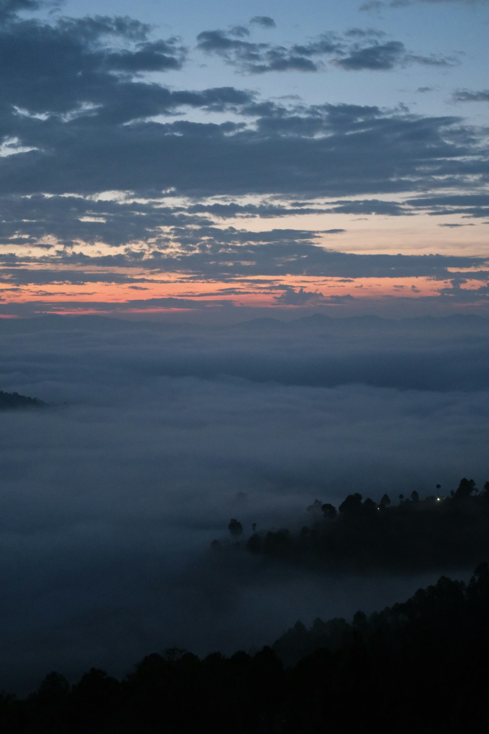 the sun is setting over a foggy valley