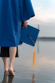 a person in a blue graduation gown holding a book