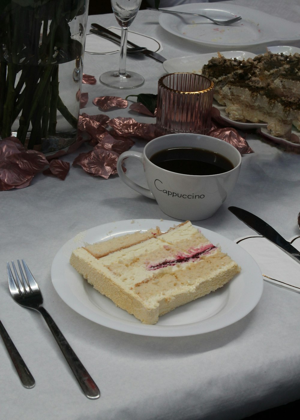a white plate topped with a piece of cake next to a cup of coffee