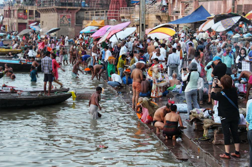 A vibrant ritual scene with devotees performing morning prayers on the ghats, colorful fabrics fluttering in the breeze.