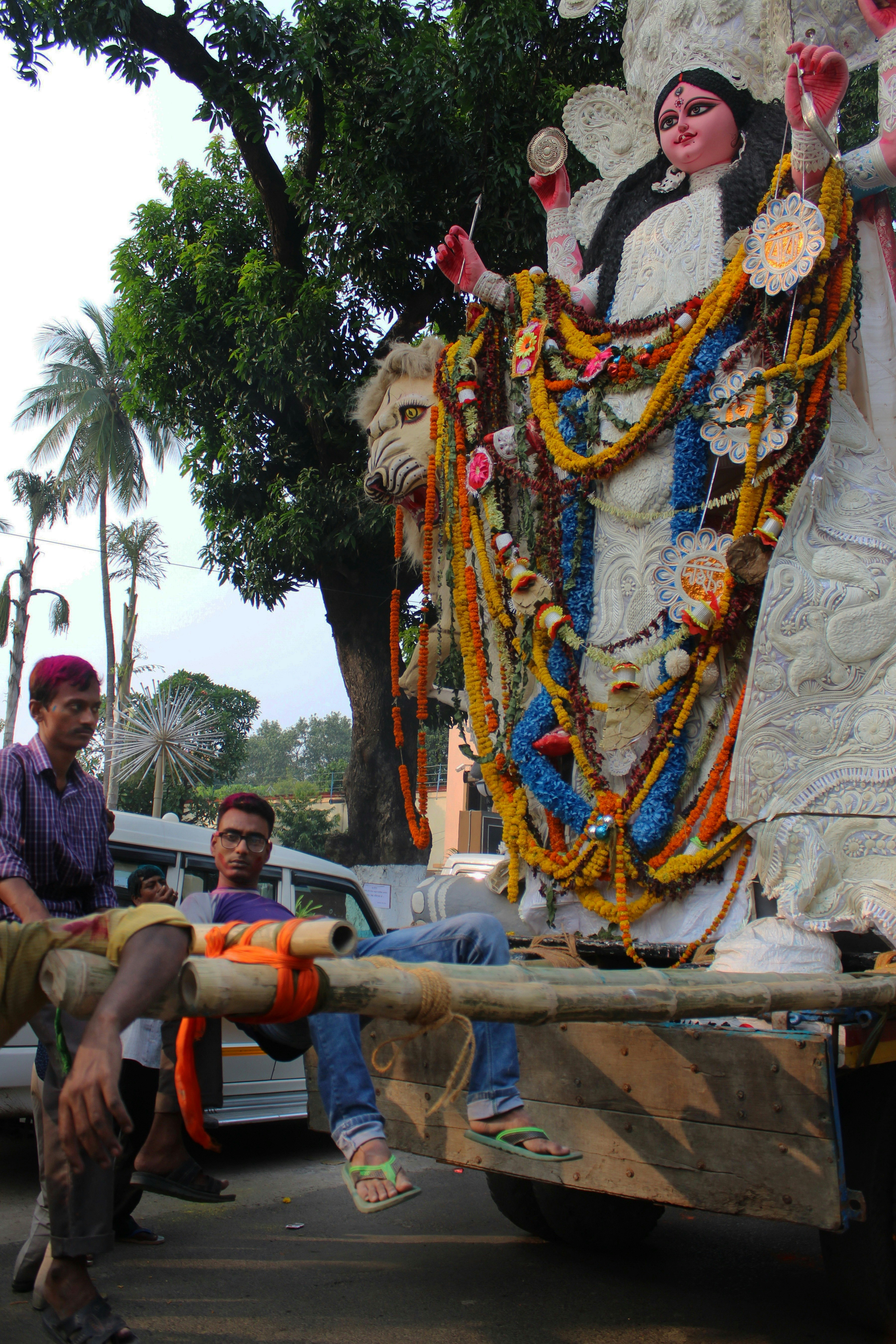 a man sitting on the back of a truck next to a statue