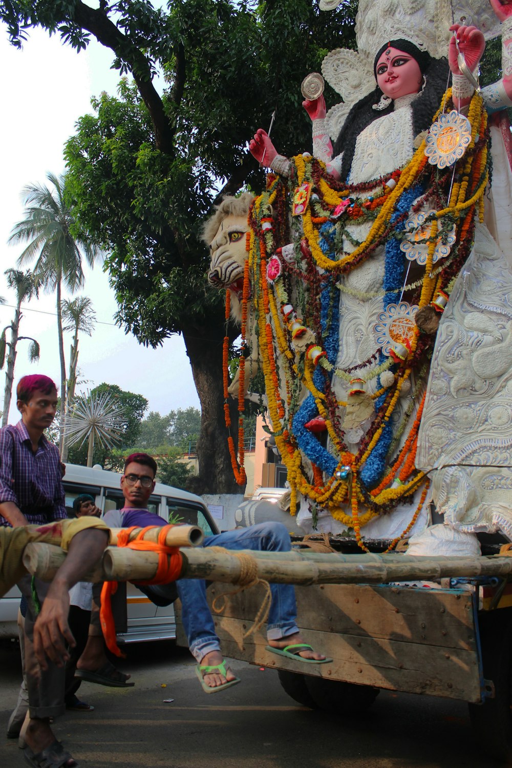 a man sitting on the back of a truck next to a statue