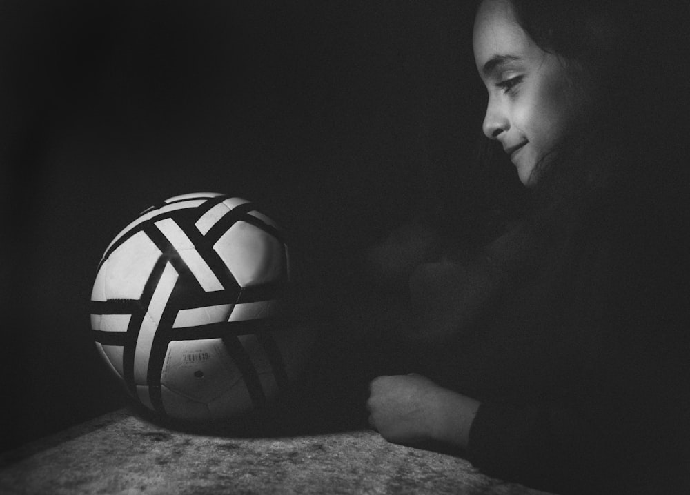 a woman sitting next to a white and black soccer ball