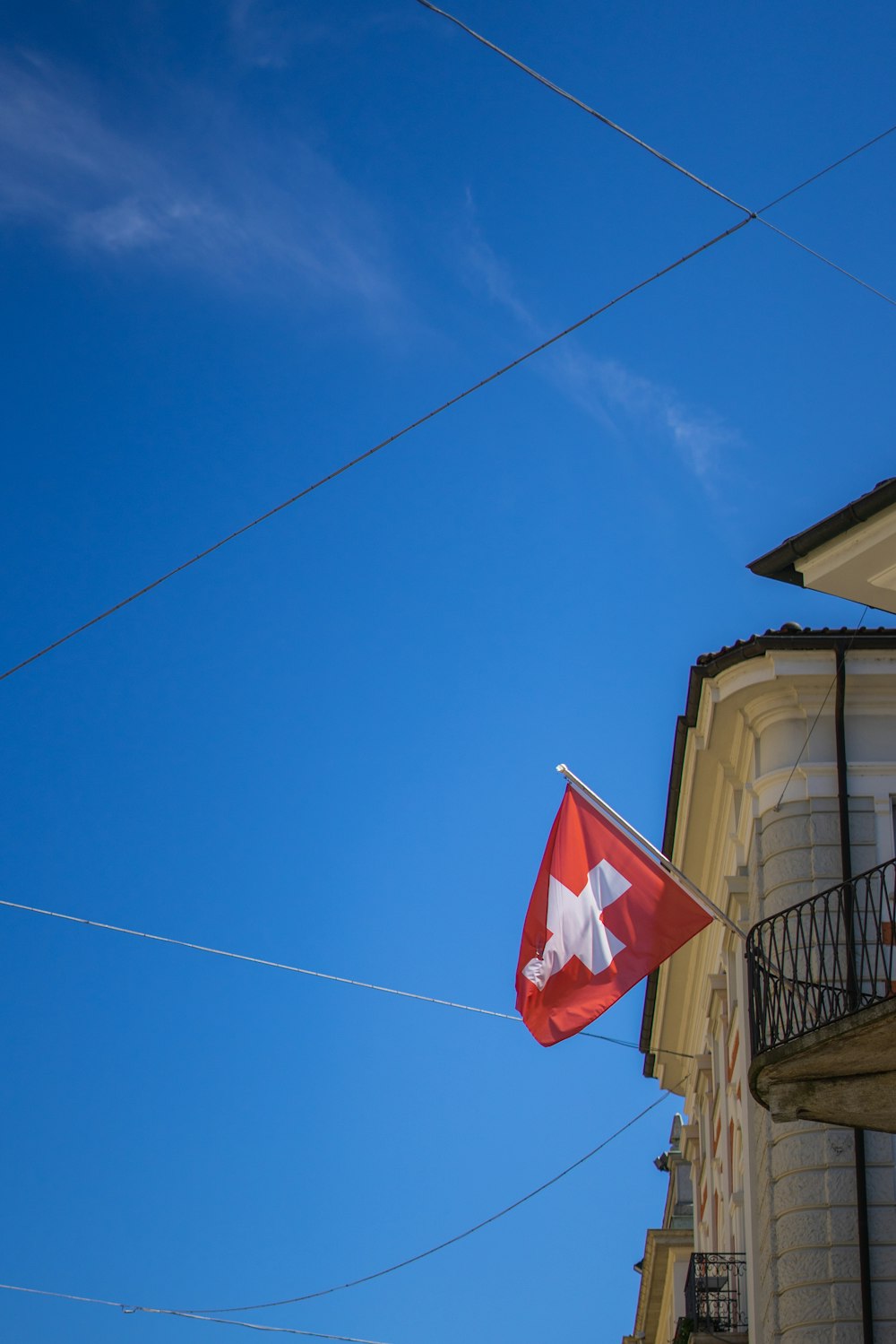 a red and white flag on a pole next to a building
