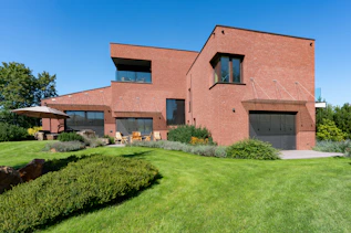 a large brick house with a green lawn in front of it