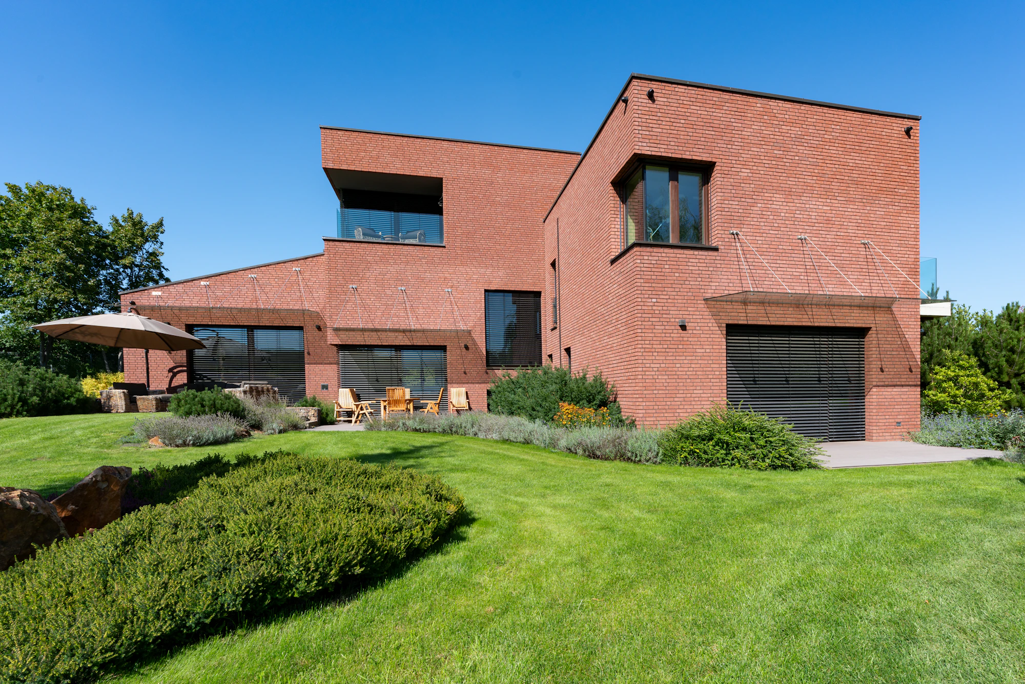 A brick house with a broad lawn and clipped hedges