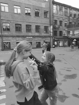Two young girls mid-dance, smiling brightly in a sunlit studio.