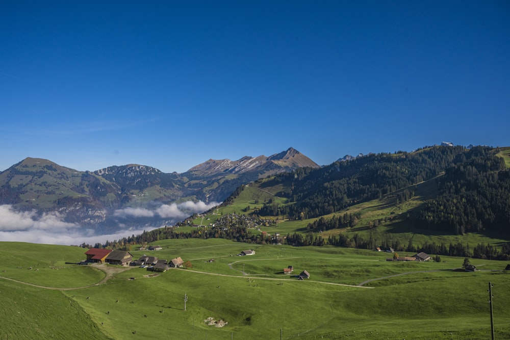 ein saftig grüner Hügel, der mit Wolken und Bergen bedeckt ist